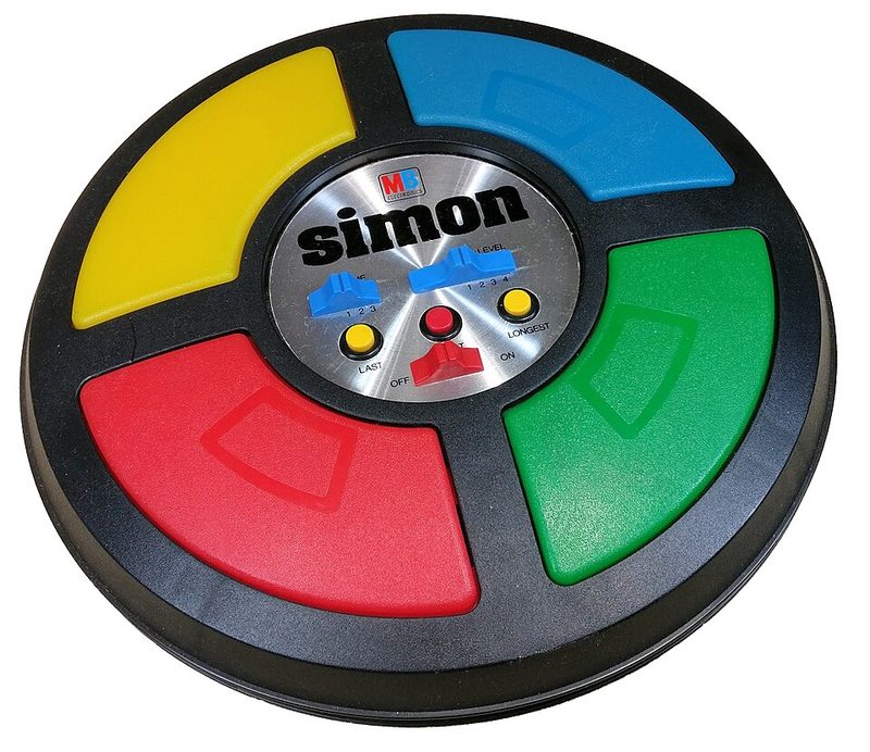 The Simon electronic game: a round black console with four large colored buttons in yellow, blue, red, and green